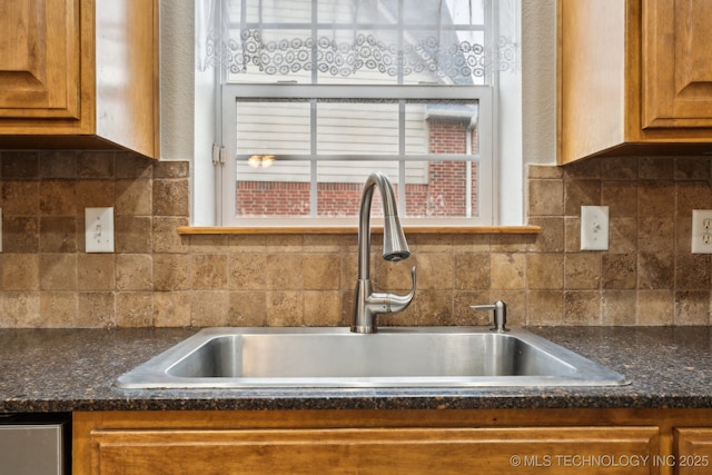 kitchen featuring tasteful backsplash, sink, and dark stone counters