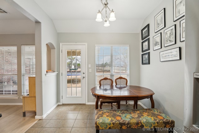 dining space with a chandelier, vaulted ceiling, and light tile patterned floors