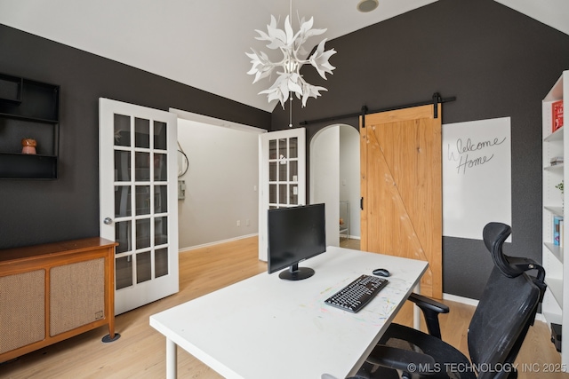 office with light hardwood / wood-style flooring, vaulted ceiling, a barn door, and french doors