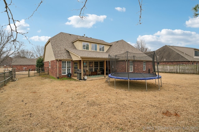 back of property with a trampoline, a lawn, and a patio