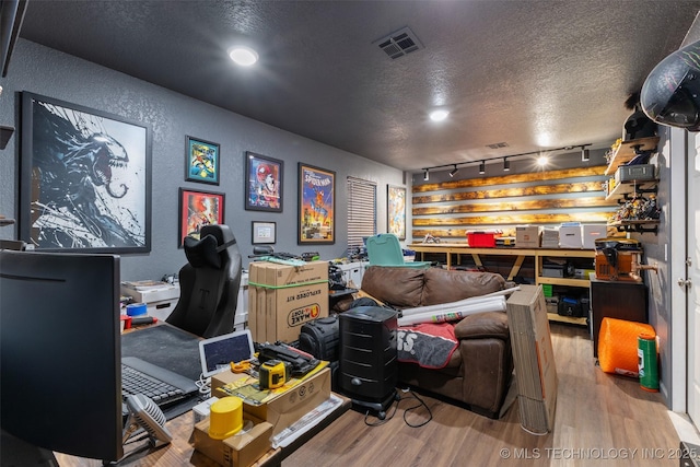 office space featuring light hardwood / wood-style floors, rail lighting, and a textured ceiling