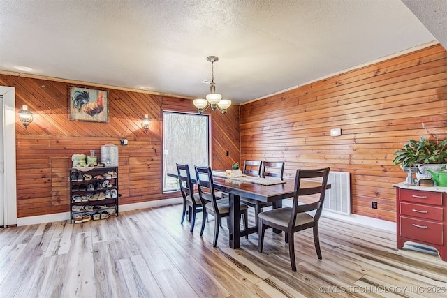 dining room with a chandelier, a textured ceiling, and light hardwood / wood-style floors