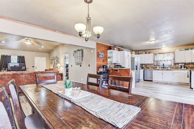 dining space featuring ceiling fan with notable chandelier and light hardwood / wood-style flooring