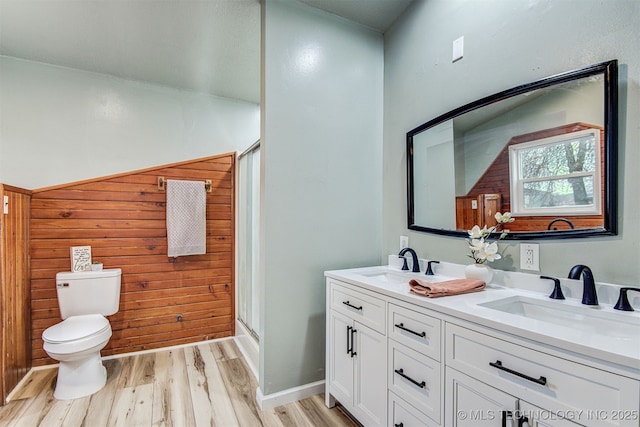 bathroom with toilet, vanity, wooden walls, a shower with door, and hardwood / wood-style floors