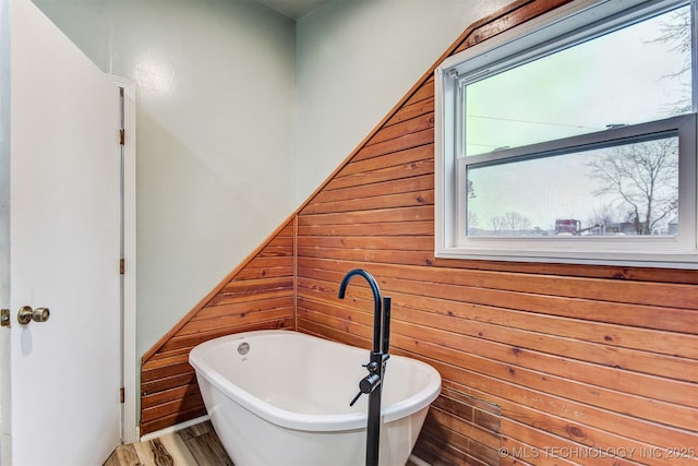 bathroom with a washtub, wood-type flooring, and wood walls