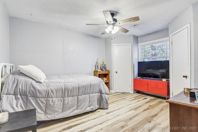 bedroom featuring ceiling fan, hardwood / wood-style floors, and a textured ceiling