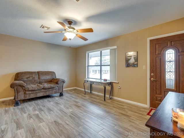 sitting room with a textured ceiling, ceiling fan, and light wood-type flooring