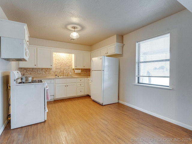 kitchen featuring sink, white appliances, light hardwood / wood-style floors, white cabinets, and decorative backsplash