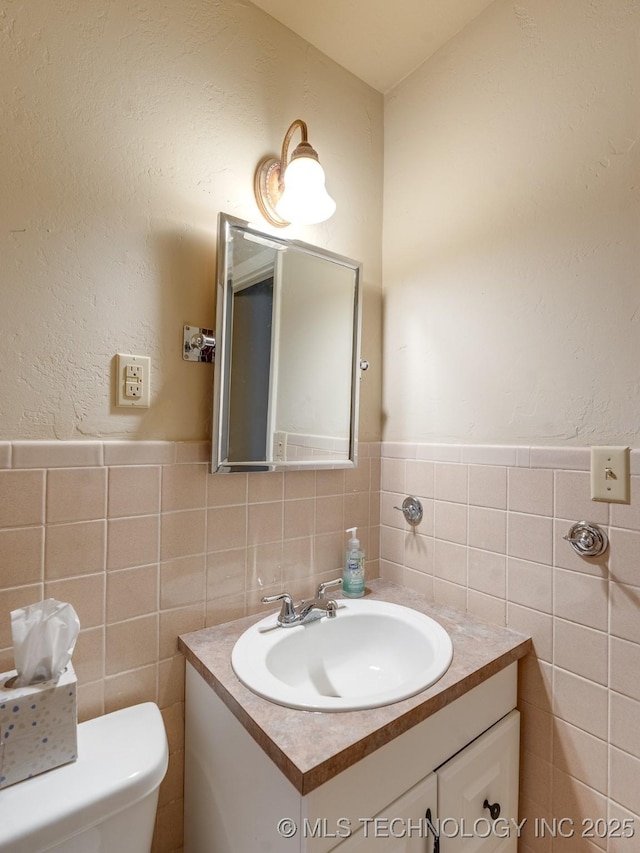 bathroom with vanity, tile walls, and toilet