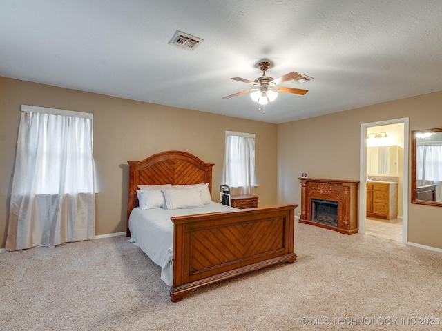 carpeted bedroom featuring ceiling fan, connected bathroom, and multiple windows