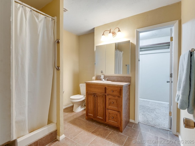 bathroom with tile patterned flooring, vanity, toilet, and walk in shower