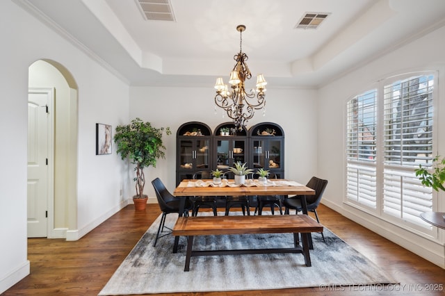 dining room with an inviting chandelier, a tray ceiling, and dark hardwood / wood-style floors