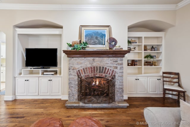 living room with crown molding, dark wood-type flooring, a fireplace, and built in shelves