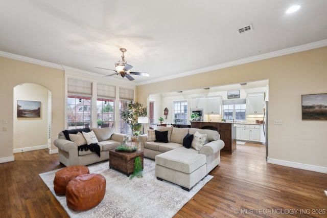 living room with crown molding, dark hardwood / wood-style floors, and ceiling fan