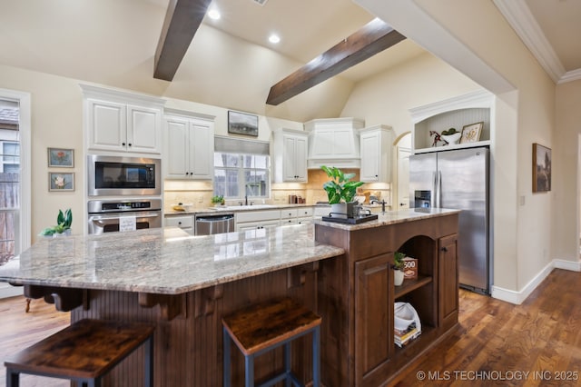 kitchen featuring white cabinetry, appliances with stainless steel finishes, a large island, and a kitchen breakfast bar