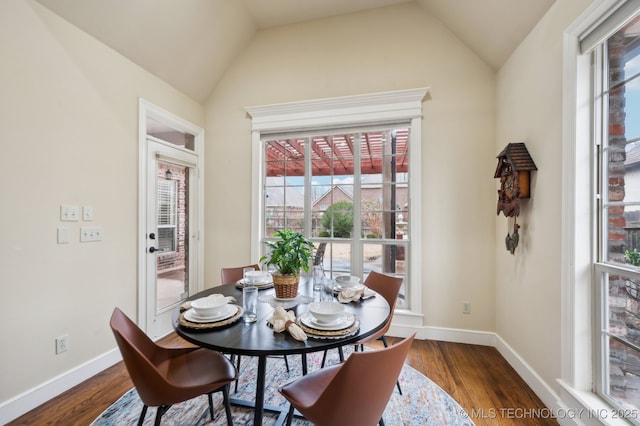 dining area with dark wood-type flooring and vaulted ceiling