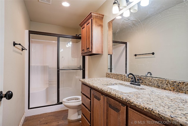 bathroom with wood-type flooring, toilet, a shower with shower door, and vanity