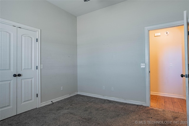 unfurnished bedroom with dark carpet and a closet