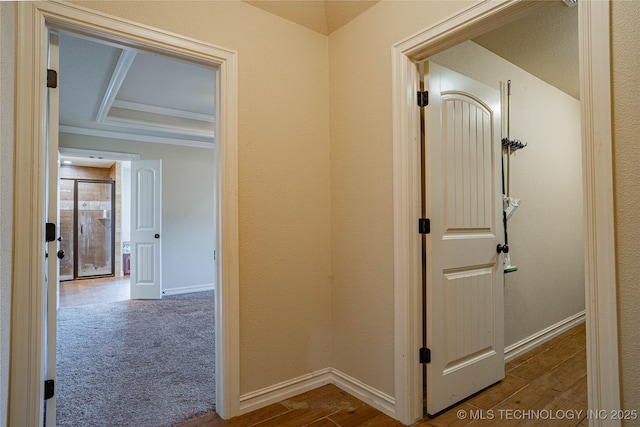 corridor with a tray ceiling, hardwood / wood-style floors, and crown molding