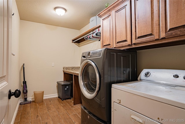 laundry room with a textured ceiling, light hardwood / wood-style flooring, cabinets, and washing machine and clothes dryer