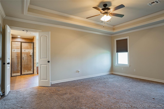 carpeted spare room with ceiling fan, ornamental molding, and a tray ceiling