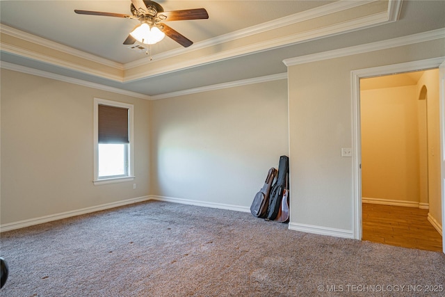 carpeted spare room featuring ceiling fan, ornamental molding, and a tray ceiling