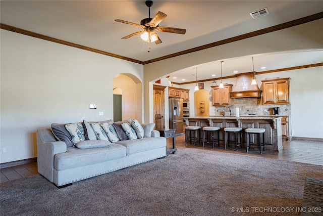 living room with ceiling fan, ornamental molding, dark hardwood / wood-style flooring, and sink