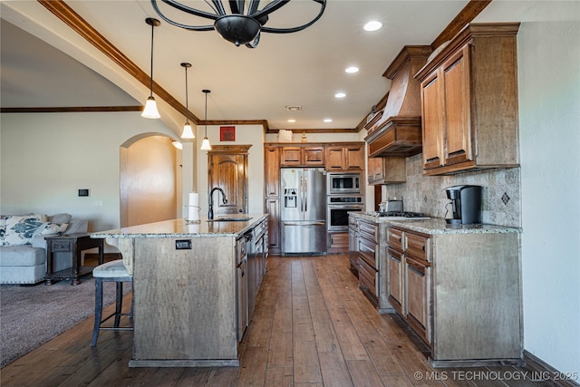 kitchen with a kitchen bar, decorative light fixtures, appliances with stainless steel finishes, a large island, and light stone countertops