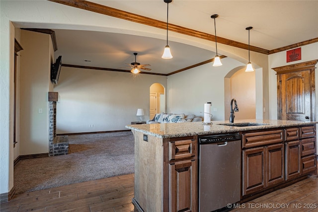 kitchen with dark wood-type flooring, sink, dishwasher, an island with sink, and light stone countertops