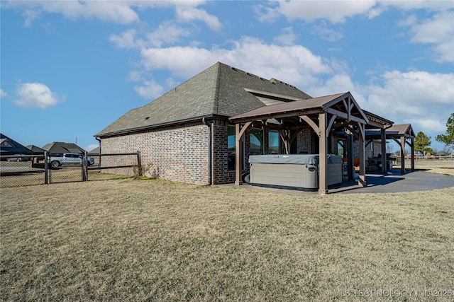 view of side of property featuring a gazebo, a yard, and a hot tub