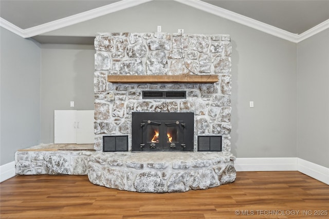 room details with hardwood / wood-style flooring, ornamental molding, and a stone fireplace