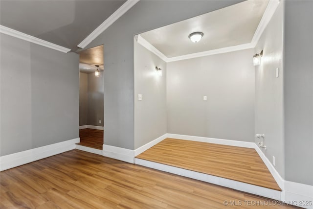 unfurnished room featuring crown molding, wood-type flooring, and vaulted ceiling