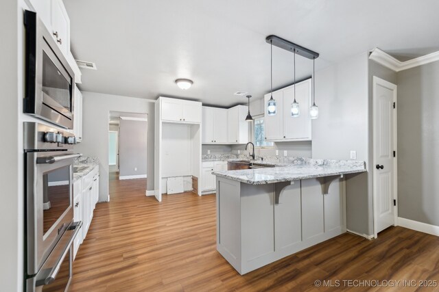 kitchen with sink, a kitchen breakfast bar, white cabinets, decorative light fixtures, and kitchen peninsula