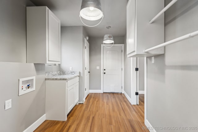 clothes washing area with cabinets, light hardwood / wood-style floors, and hookup for a washing machine