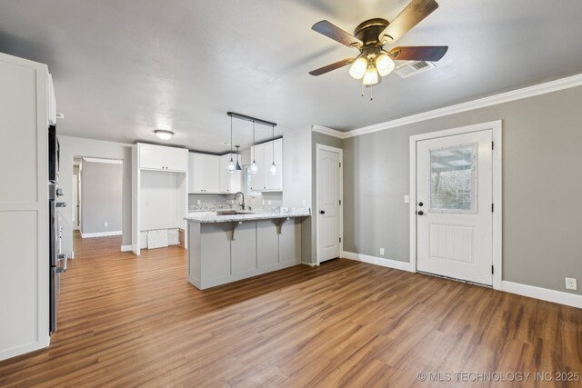 kitchen featuring appliances with stainless steel finishes, decorative light fixtures, light stone countertops, and white cabinets