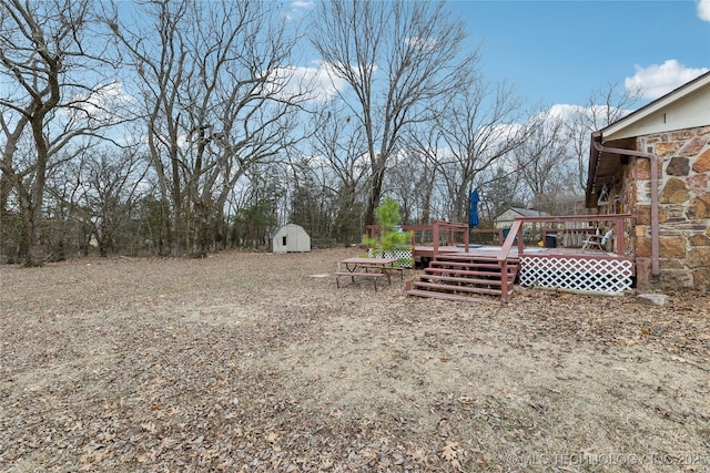 view of yard featuring a wooden deck and a storage unit