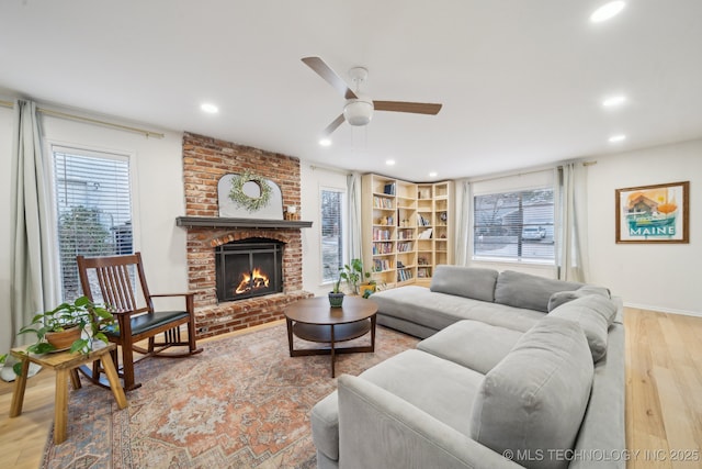 living room with a fireplace, light hardwood / wood-style flooring, and ceiling fan