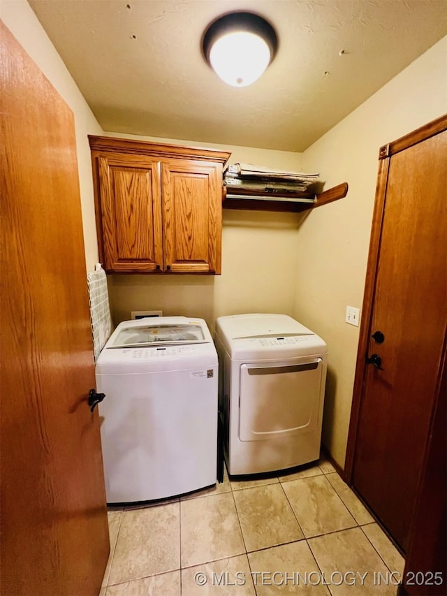 laundry room with washing machine and dryer, cabinets, and light tile patterned flooring