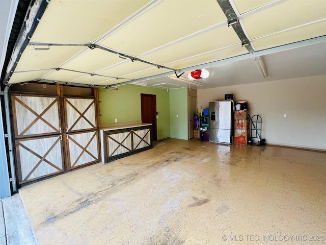 garage featuring a garage door opener and stainless steel refrigerator with ice dispenser