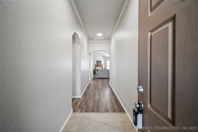 corridor featuring ornamental molding and light tile patterned floors