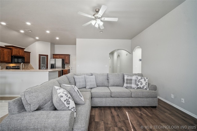 living room featuring dark hardwood / wood-style flooring, vaulted ceiling, and ceiling fan