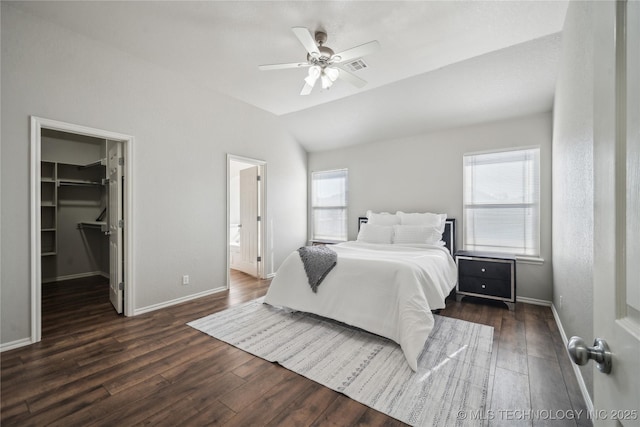 bedroom with lofted ceiling, a walk in closet, dark hardwood / wood-style floors, a closet, and ceiling fan