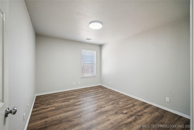 empty room featuring dark hardwood / wood-style floors and a textured ceiling