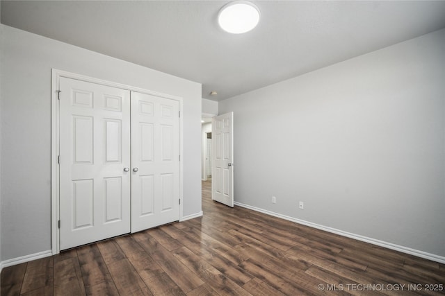 unfurnished bedroom with dark wood-type flooring and a closet