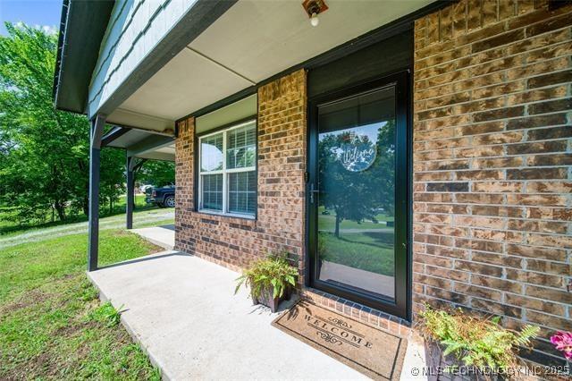 property entrance with a lawn and covered porch