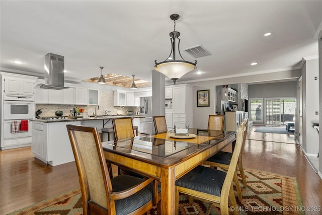 dining space featuring dark wood-type flooring, ornamental molding, and sink