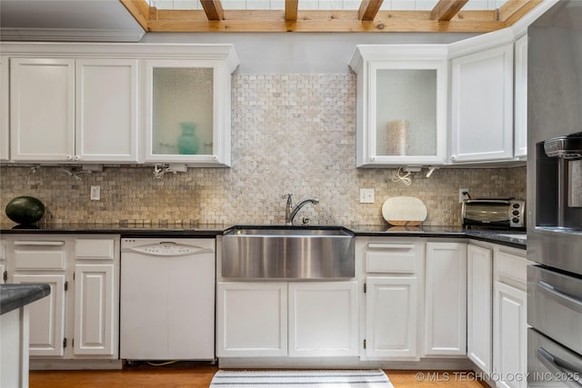 kitchen featuring a skylight, tasteful backsplash, white cabinetry, dishwasher, and sink