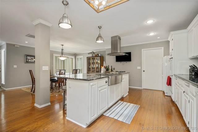 kitchen with white cabinetry, decorative light fixtures, a kitchen island, island exhaust hood, and dark stone counters