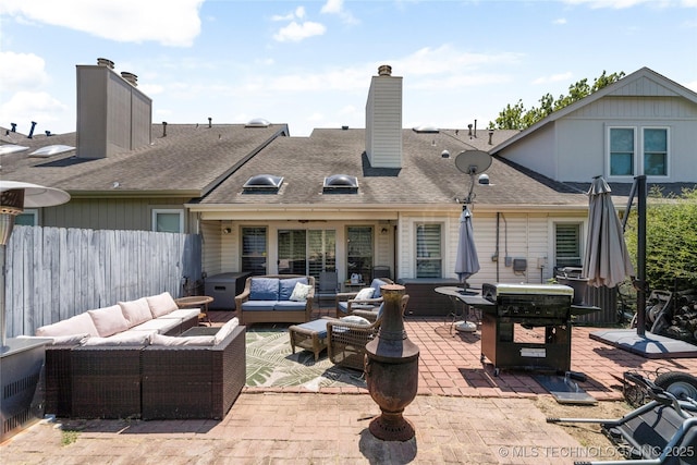 rear view of house featuring an outdoor living space with a fire pit and a patio