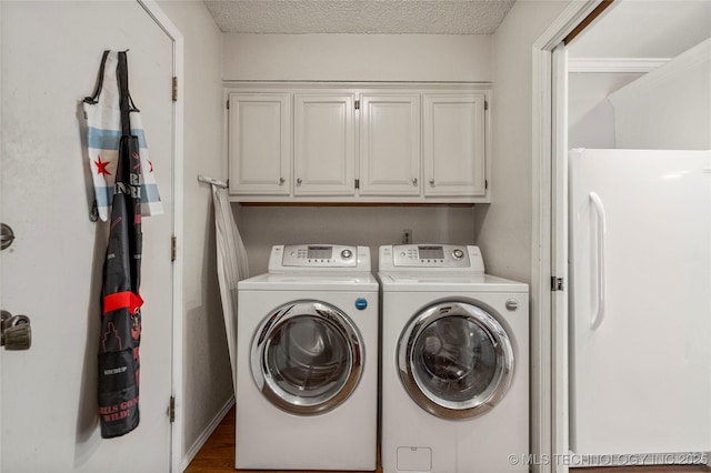 clothes washing area featuring cabinets, a textured ceiling, and independent washer and dryer